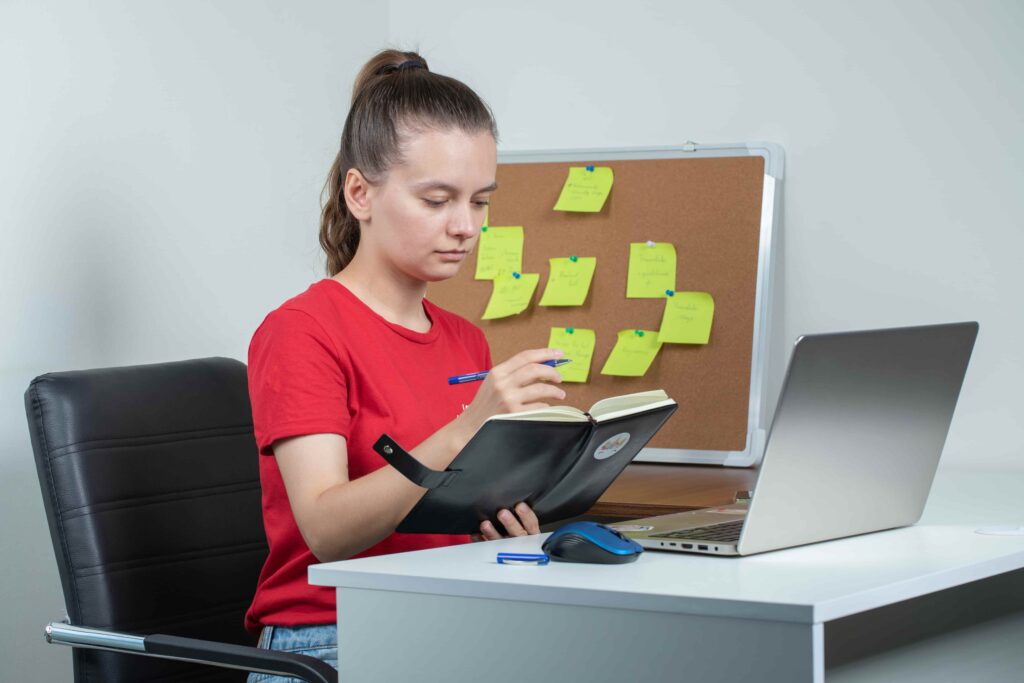 female employee working laptop taking notes 1